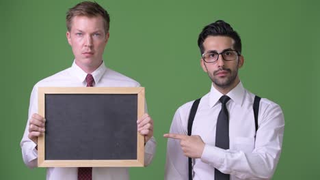 two young multi-ethnic businessmen working together against green background