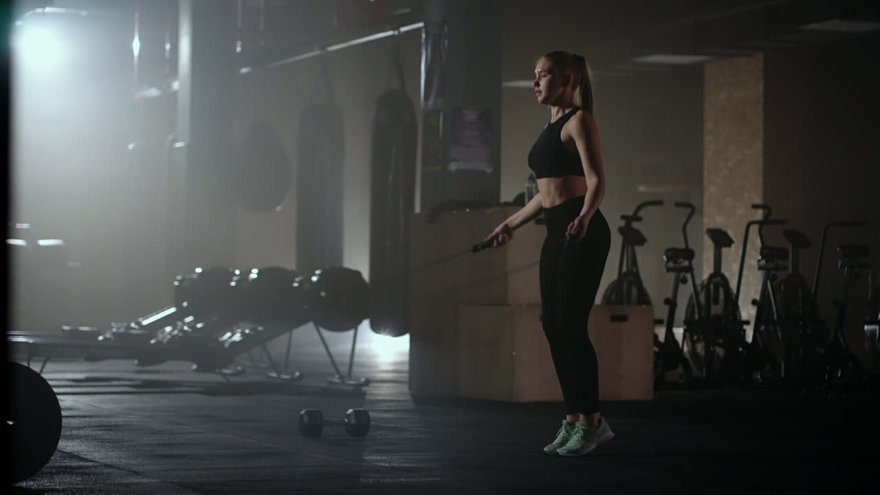 Slow motion: Young woman skipping rope. woman jump roping in the gym as part of her workout routine determined woman focused