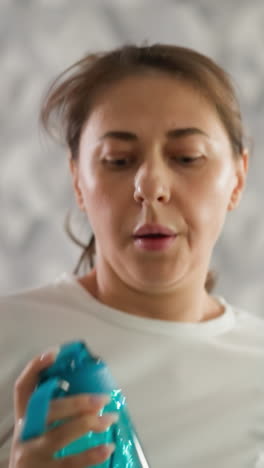 mujer con botella de agua corre en el entrenador en casa. mujer enfocada en los mejores ejercicios en la cinta de correr sosteniendo una bebida en el gimnasio doméstico. afición deportiva saludable