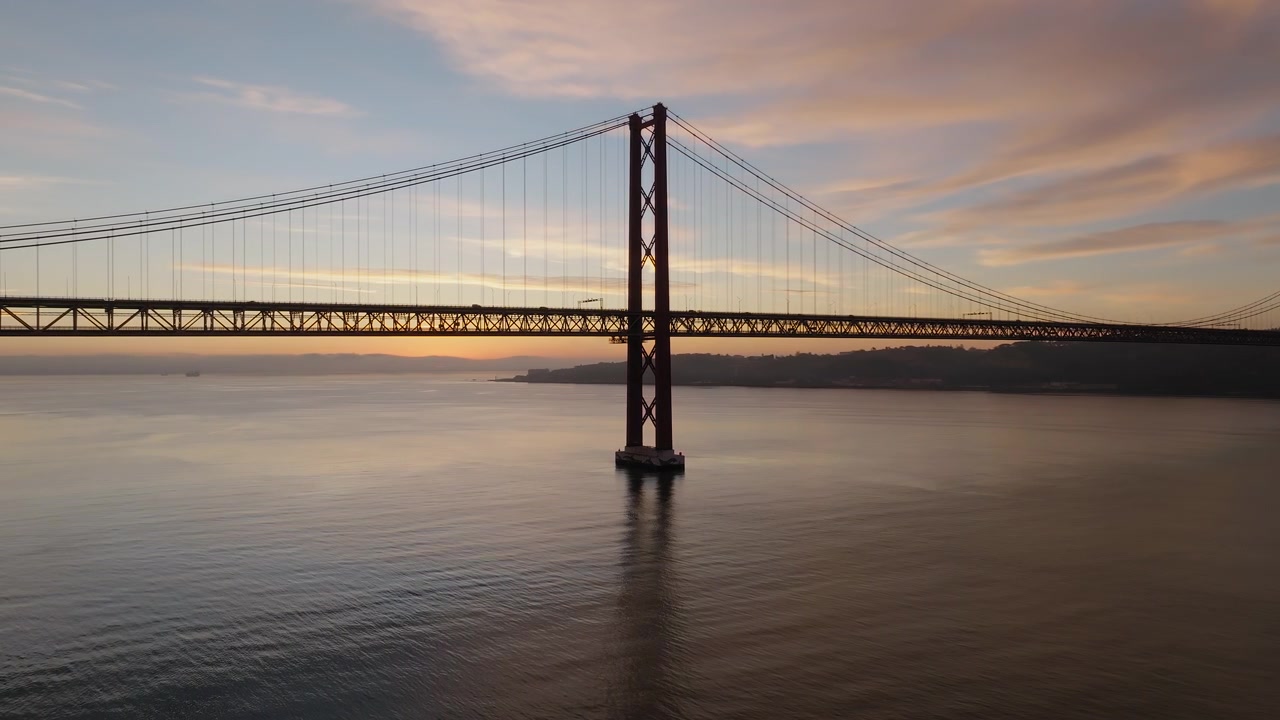 Ponte 25 Aprile sul fiume Tago durante l'alba a Lisbona, orbita di allontanamento del drone