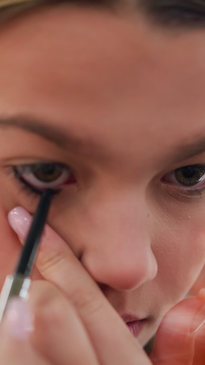 Teen girl makeup, Closeup of teenager perfecting her eyeliner application technique, Teenager demonstrating meticulous eyeliner skills for clean aesthetic appearance and recording vibe