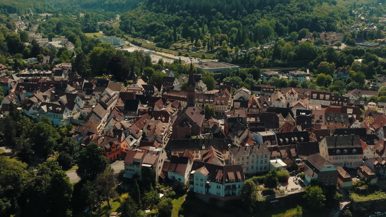 Gli storici tetti rossi e le vie strette di una città tedesca, incentrati sul campanile di una chiesa importante, con la lussureggiante foresta verde di Odenwald e le colline che circondano l'area residenziale