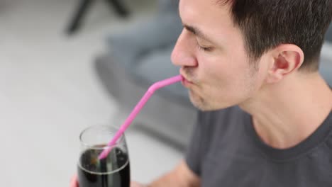 close-up of a man drinking a beverage with a pink straw