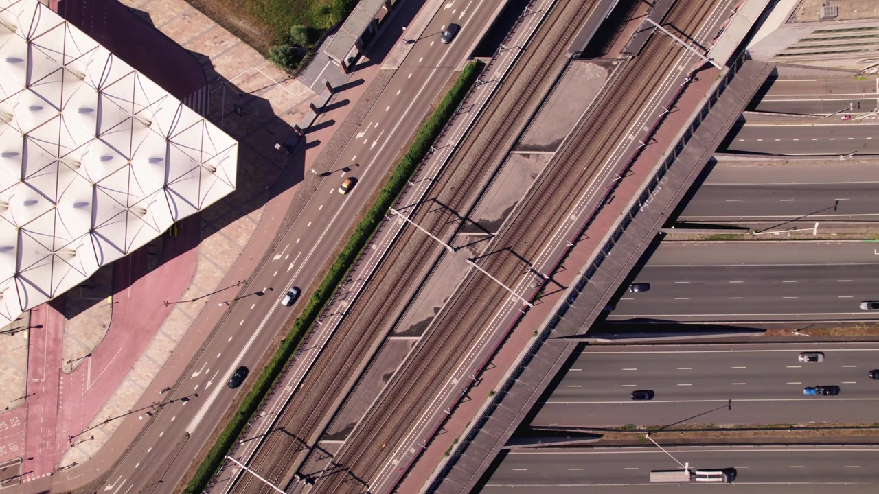 Ripresa aerea stabile dall'alto della costruzione grafica del soffitto triangolare della stazione degli autobus di Leidsche Rijn con binari ferroviari e autostrada che passano accanto e sotto di essa