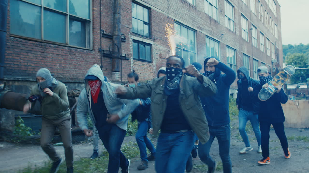 빈민가에서 달리고 공격하는 얼굴에 스카프를 두른 다민족 젊은이들