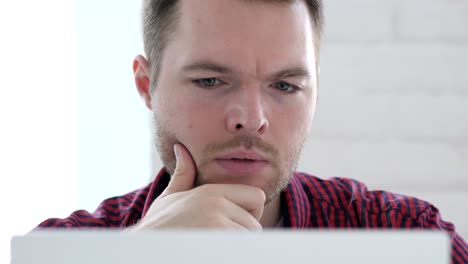 pensive young man thinking and working on laptop, front close up