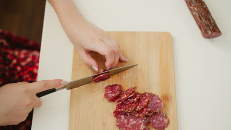 woman slicing sausage on a wooden cutting board
