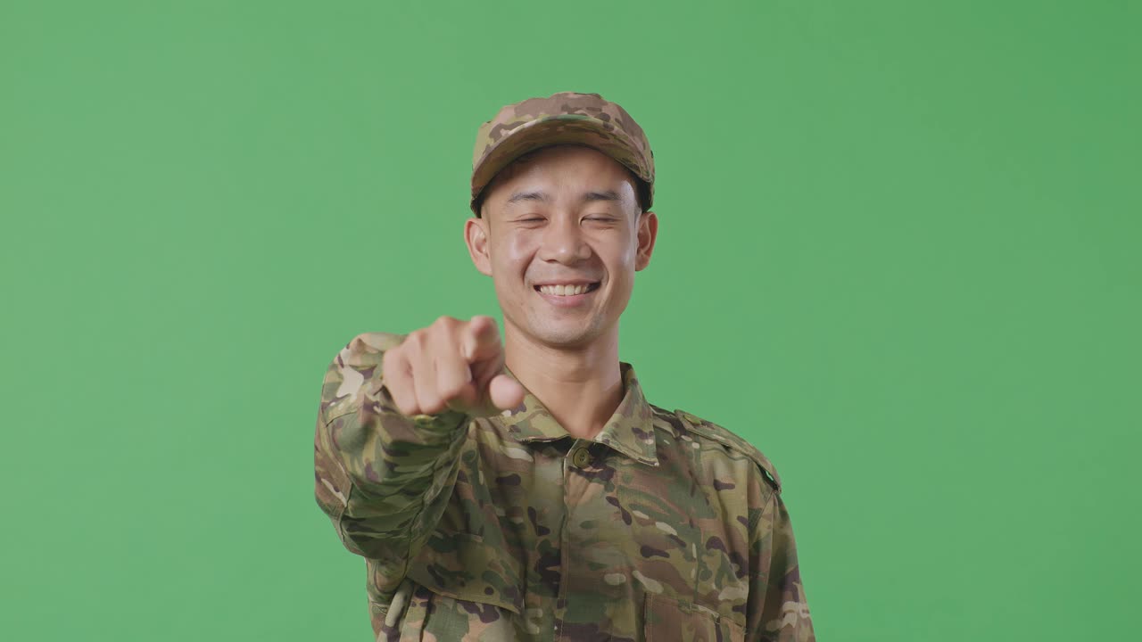 Close Up Of Asian Man Soldier Smiling And Touching His Chest Then Pointing At You While Standing In The Green Screen Background Studio