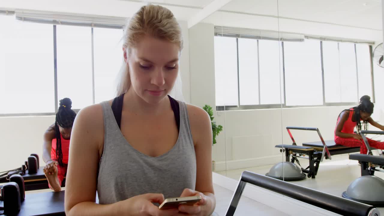 mujer usando teléfono móvil en el estudio de fitness 4k