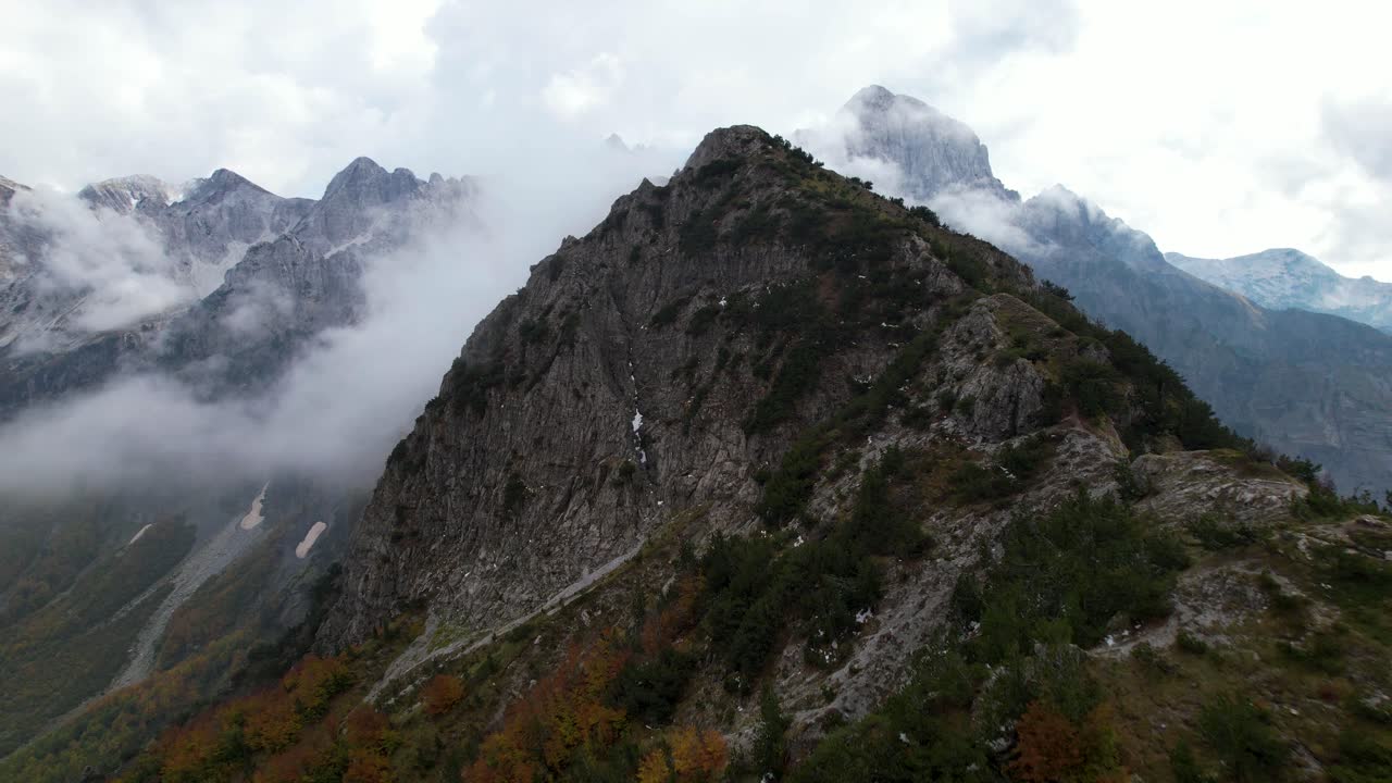 pico de montaña en los alpes con fondo brumoso y follaje colorido en otoño