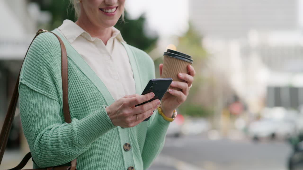 Woman with coffee using smartphone on city street