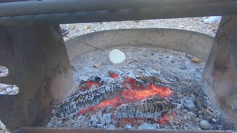 모닥불 숯불 위에 황금색으로 굽는 큰 흰색 마시멜로