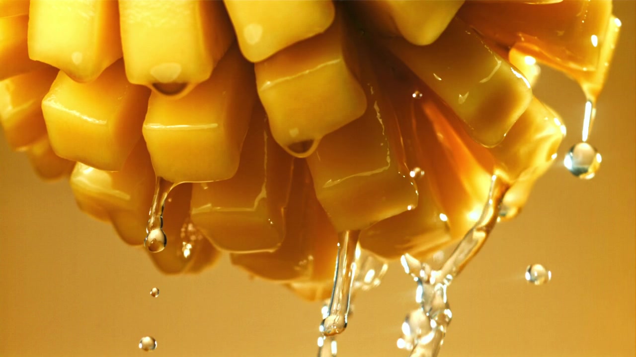 Acqua che gocciola al rallentatore da mango fresco a cubetti