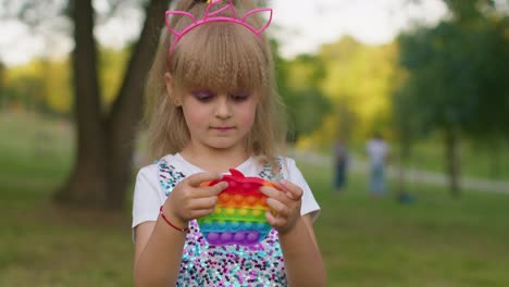 child girl kid playing squeezing anti-stress pop it touch screen toys simple dimple game in park