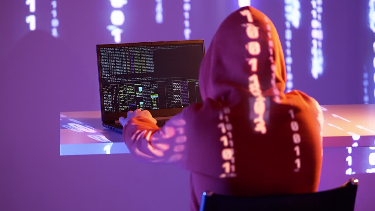 Hooded figure types on a laptop in a dark neon room as binary code glows across their back. Terminal commands and digital symbols suggest hacking, coding or penetration testing activity