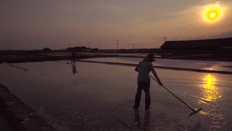silhouette pair of workers in the setting sun on tsalt fields in south east asia