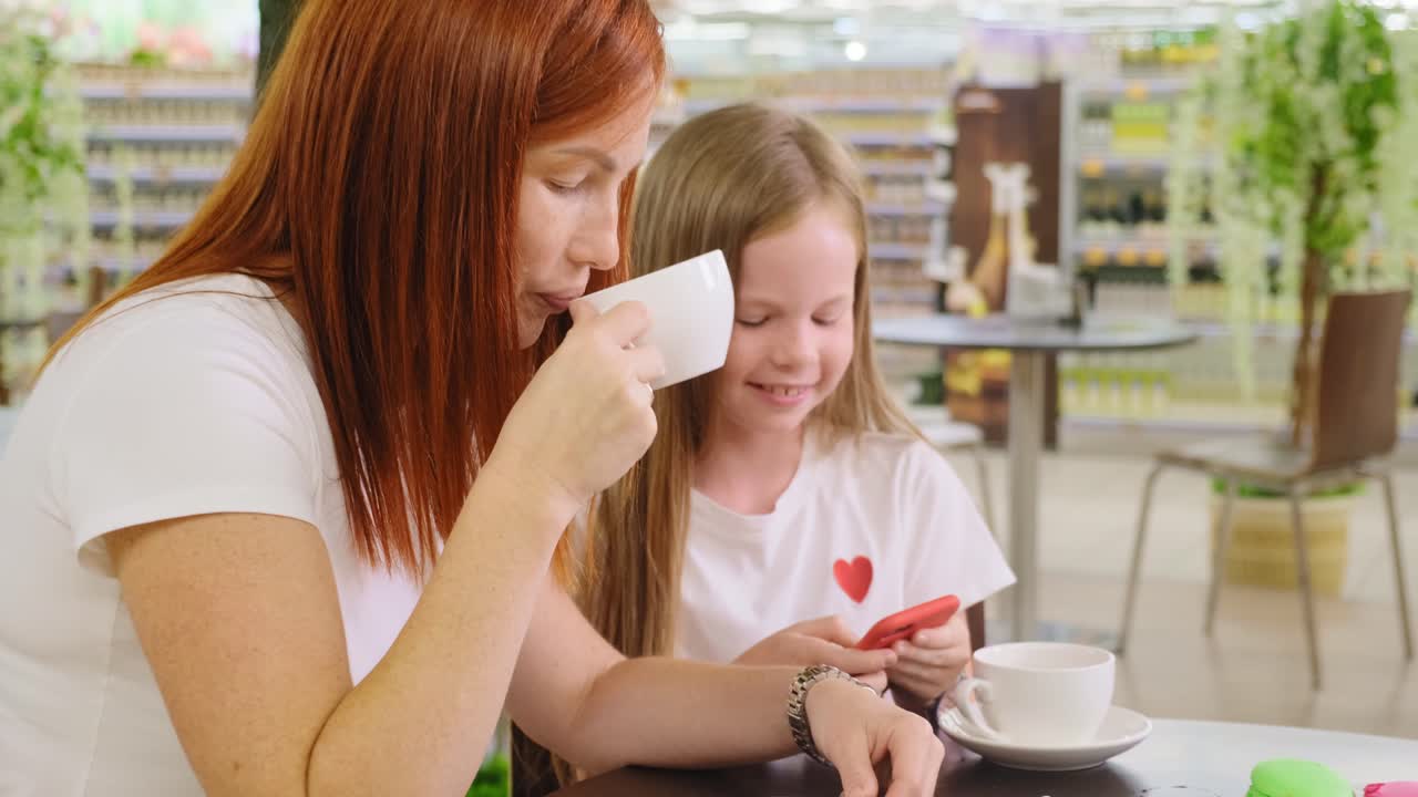 Mother and daughter enjoying a coffee break in a shopping mall