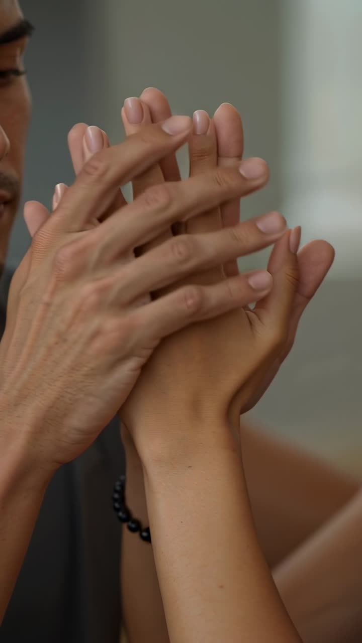 Vertical video: From tight clasp, couple hands shifting into rubbing at home for comfort, gold ring