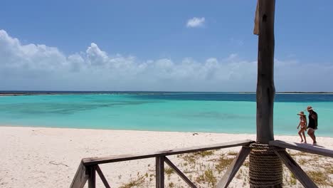 Junges-Paar-Romantischer-Spaziergang-Am-Weißen-Sandstrand-Zusammen-Mit-Dem-Ozean-Dahinter,-Weitwinkel