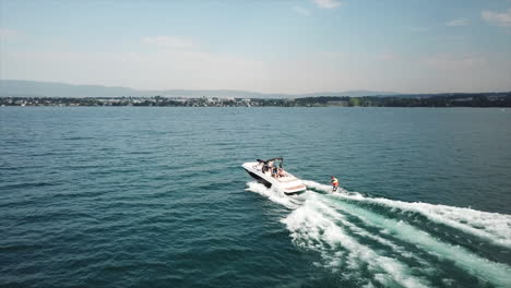vista aérea de drones de un barco navegando en el lago de ginebra, un atleta está haciendo wakesurf, suiza