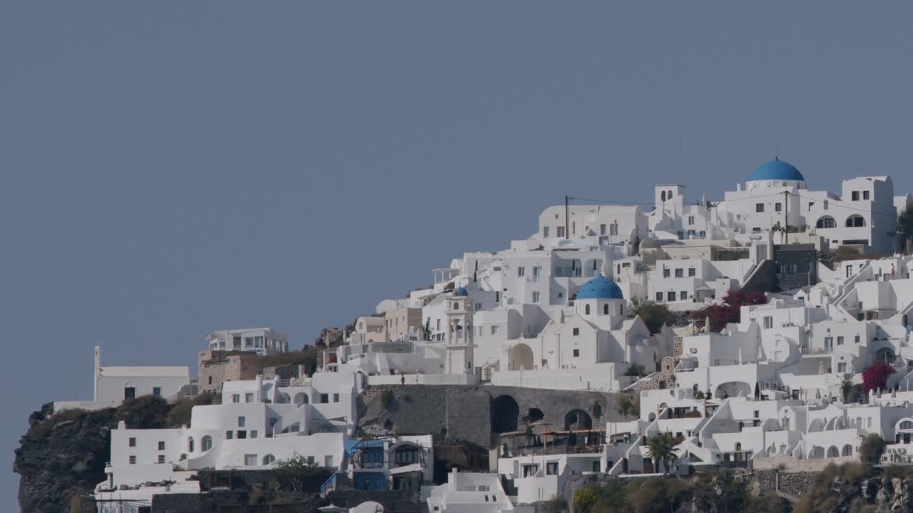 casas encaladas con cúpulas azules en un acantilado en fira, santorini, grecia bajo un cielo azul claro