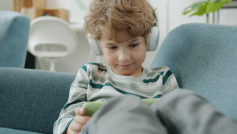 boy listening to music and using tablet on couch