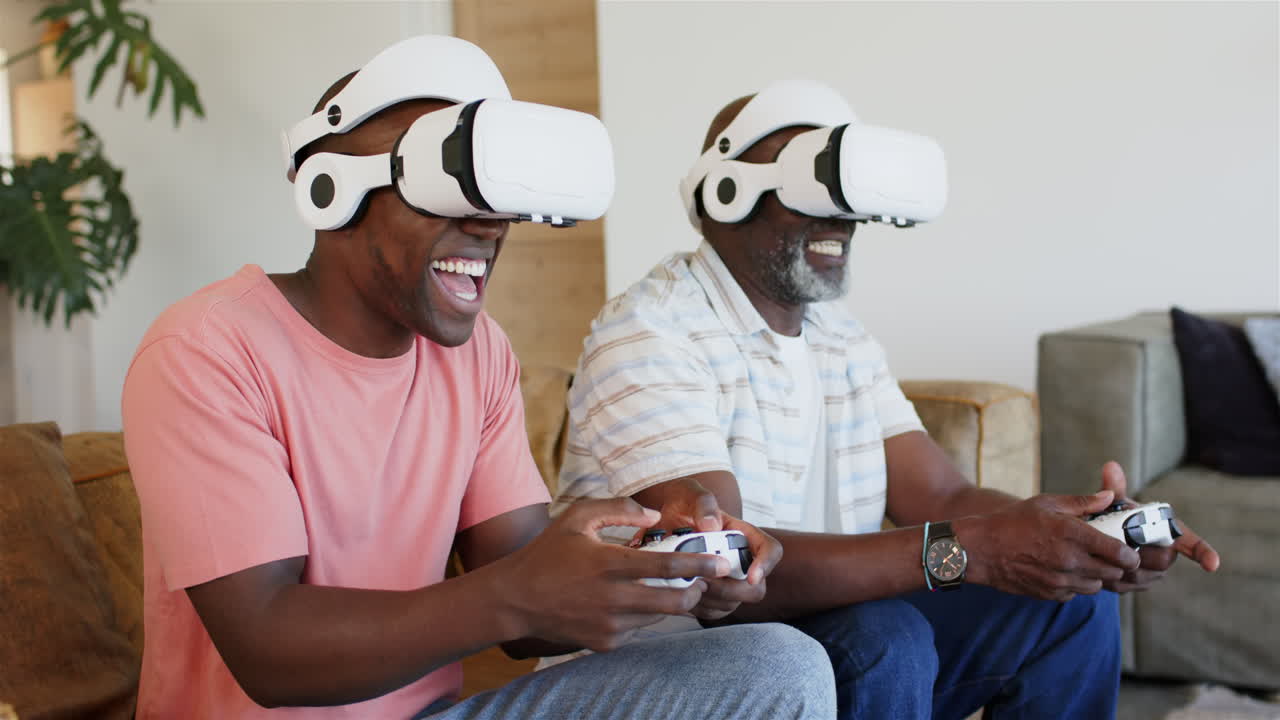 Playing video games, father and adult son wearing VR headsets and holding controllers, smiling