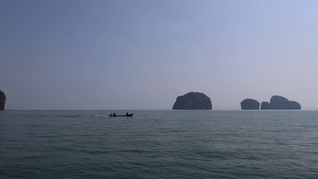 작은 배가 섬들과 함께 조용한 바다를 가로질러 이동합니다.