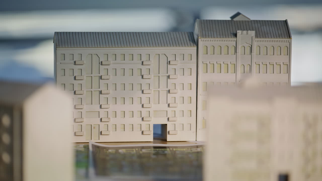 Modell av bostadsområde placerad på kontorsbord med byggnadsdokument i närbild