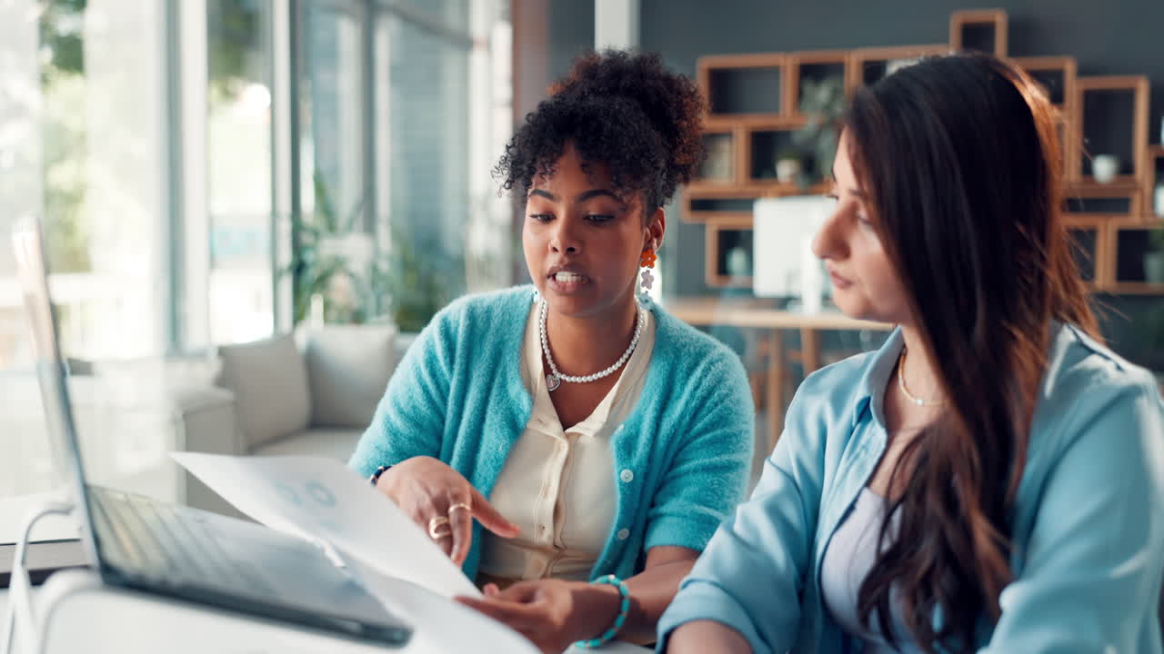 Two Women Discussing Documents and Collaborating in a Modern Office