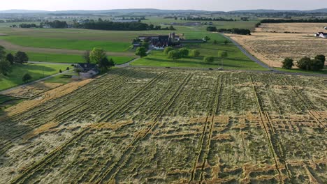 fresh cut farm field in american countryside. aerial flyover shot. sunny day in summer. wide shot. farmstead in america. cropland farmland harvesting