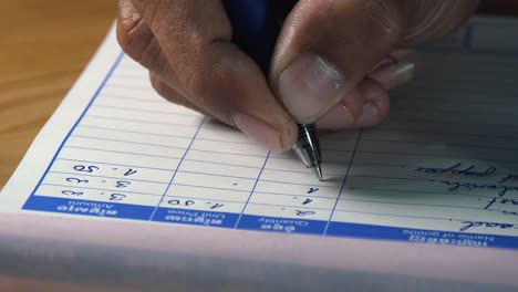 close shot of a men writing a bill