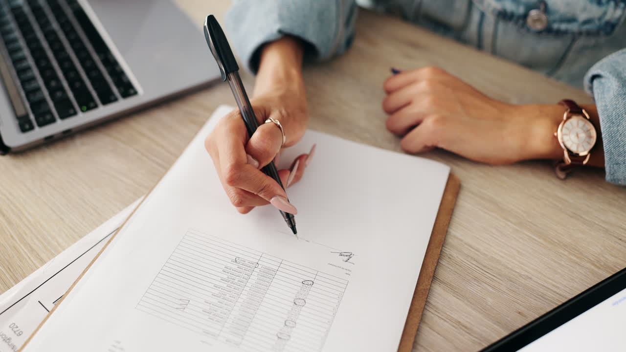 A woman is writing on a document with a pen