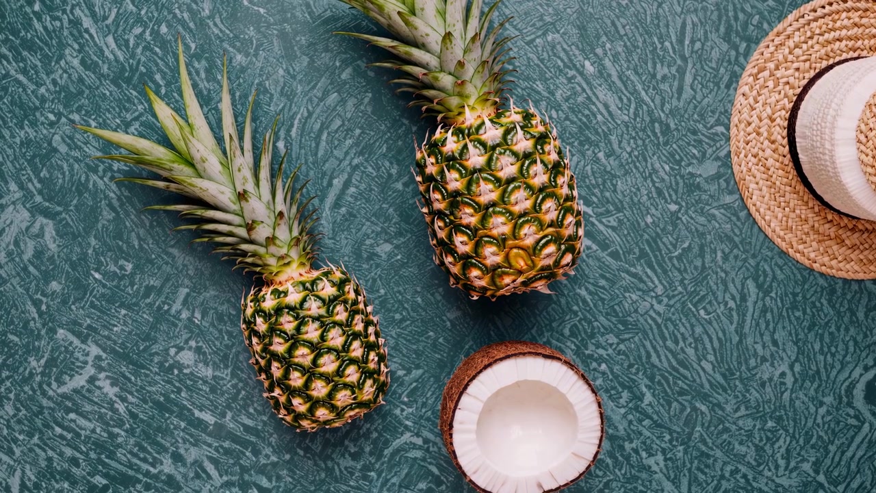 Composizione tropicale con ananas, cocco e cappello di paglia