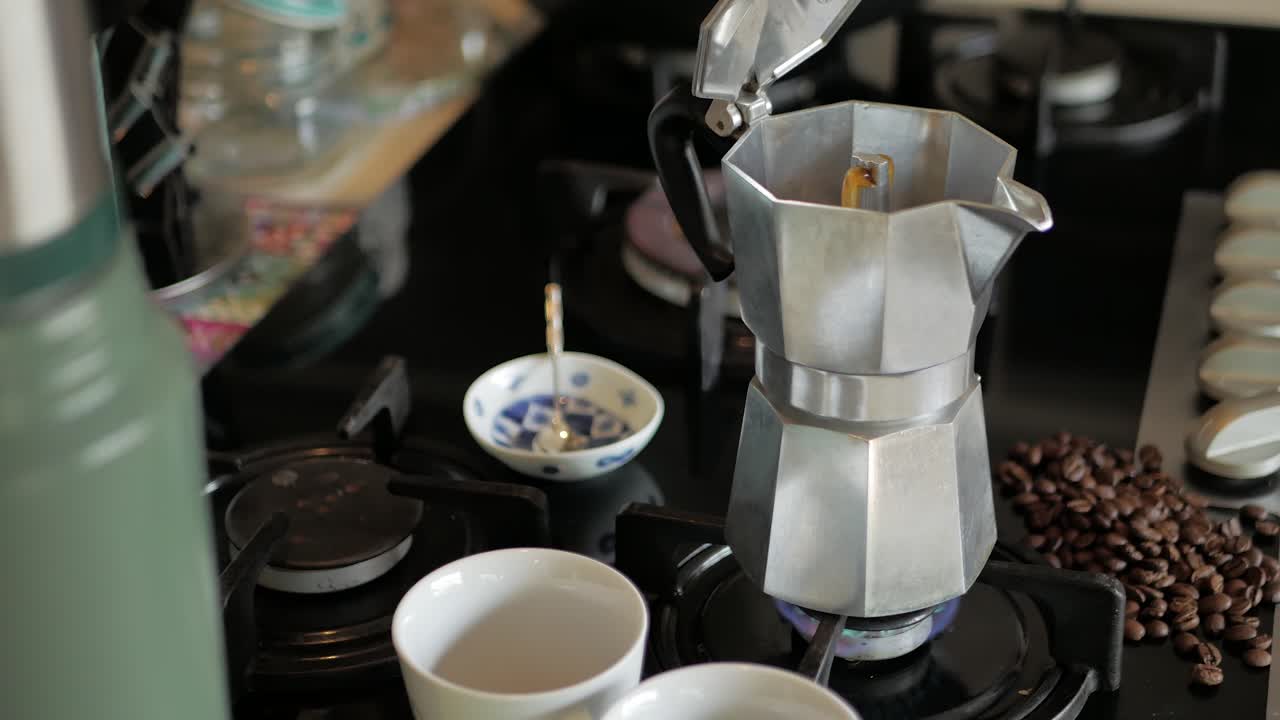 가스 불꽃에 모카 익스프레스가 커피를 분출하고 가장자리 위로 약간의 액체를 쏜다.