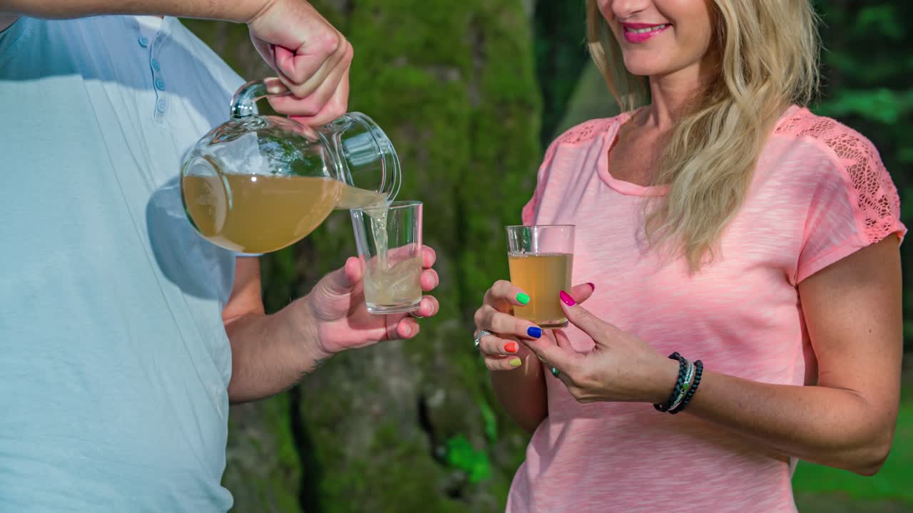 Man's hands pour out drinks to young woman. Slow motion