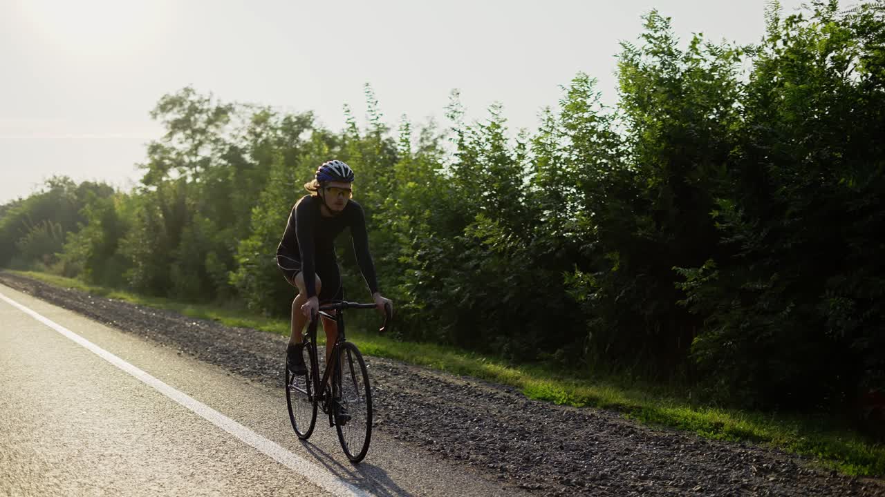 Mandlig cyklist med hjelm cykler langs en tom bane i slowmotion.