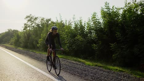 Male-cyclist-in-helmet-rides-bicycle-along-an-empty-track,-slow-motion