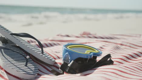 primer plano de gafas, chanclas y toalla en la playa, en cámara lenta, con espacio para copiar