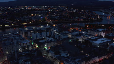 Aerial-view-of-various-buildings-in-town.-Shannon-river-calmly-flowing-through-night-city.-Limerick,-Ireland