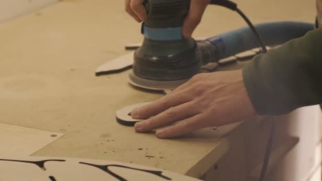 a carpenter grinds a piece of wood, plywood product made on a cnc laser machine with a grinder