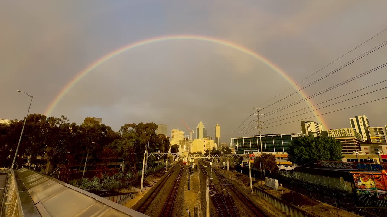 arco iris sobre las vías del tren de perth y cbd, australia occidental en el día del cielo gris