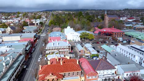 high-angle drone footage glides above armidale’s main street, revealing historic buildings, tree-lined roads, and overcast winter skies with steady forward movement