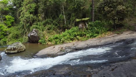 Wunderschöne-Sequenzaufnahme-Einer-Drohne,-Die-Einen-Wasserfall-Sehr-Nahe-Am-Wasser-Hinabsteigt,-Umgeben-Von-Bäumen-Und-Natur