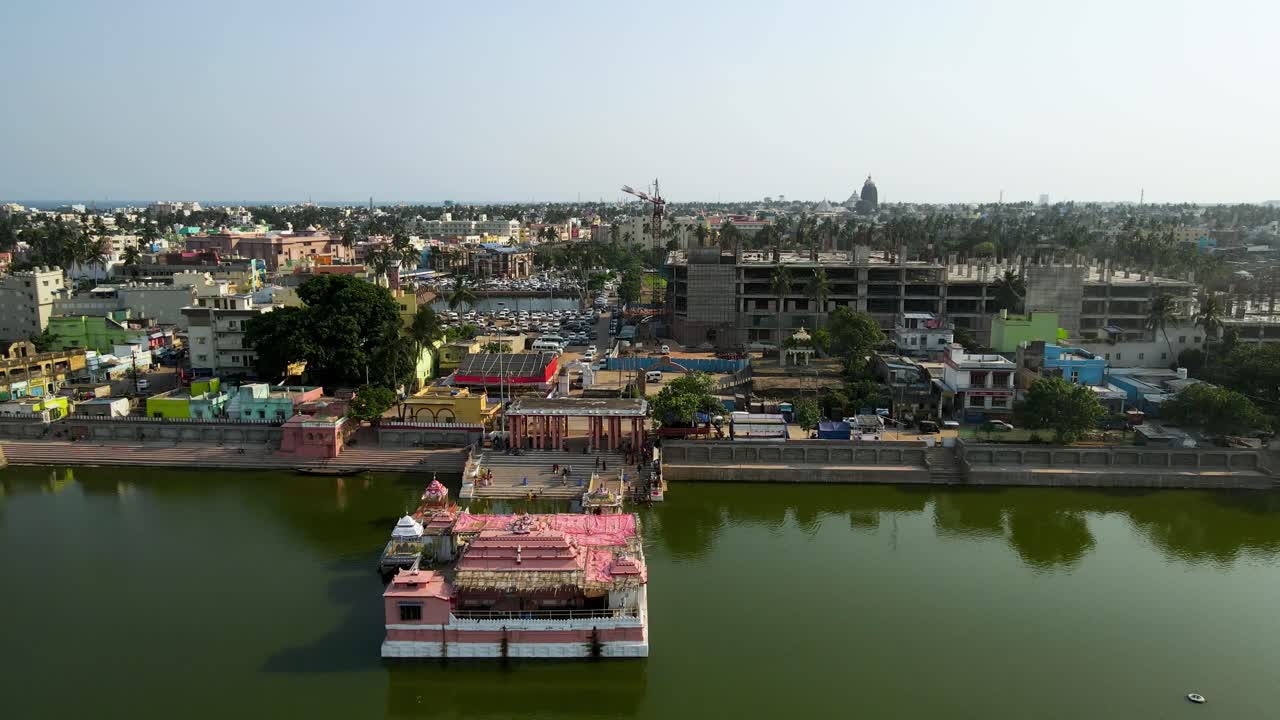 Aerial drone shot of Jagannath Puri at dusk, with the temple glowing in the city lights and the horizon in the distance.