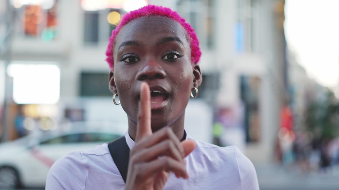Young Woman with Pink Hair Making a Shhh Gesture and Smiling