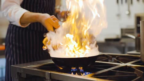 slow motion chef sets pan on fire in professional kitchen close up on pan