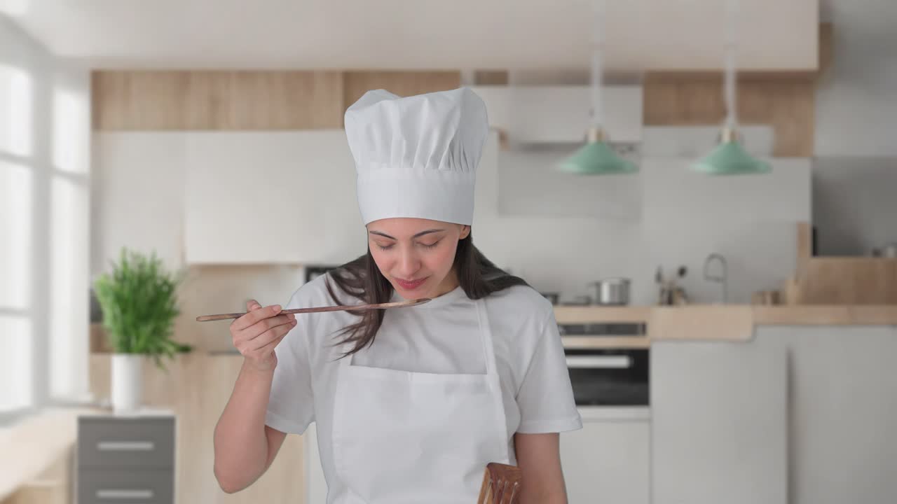 una mujer india feliz, chef profesional, probando buena comida.