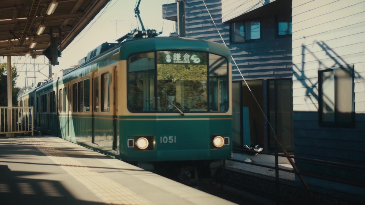 El tren Enoden vintage verde y crema llega a una plataforma directamente junto a las casas, una característica distintiva de esta estrecha línea ferroviaria costera que conecta Kamakura y Enoshima, Japón