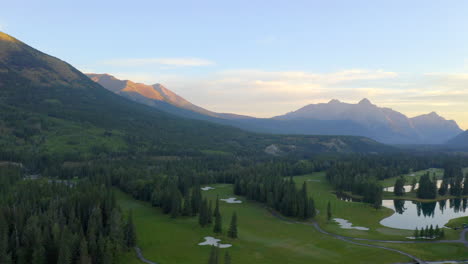 Vista-Aérea-De-Drones-Del-Campo-De-Golf-Verde-En-Las-Montañas-Rocosas-De-Banff-Y-Kananaskis-De-Alberta,-Canadá-Al-Amanecer-En-La-Mañana